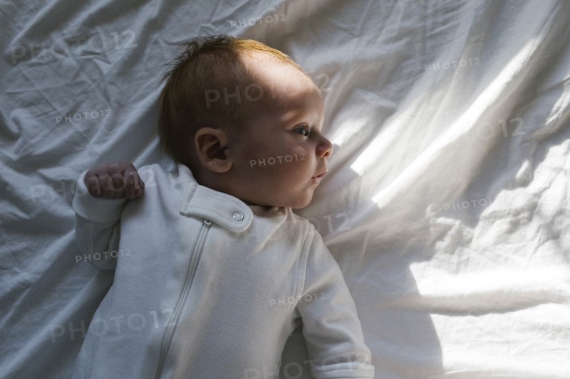 Baby boy (2-5 months) lying on bed