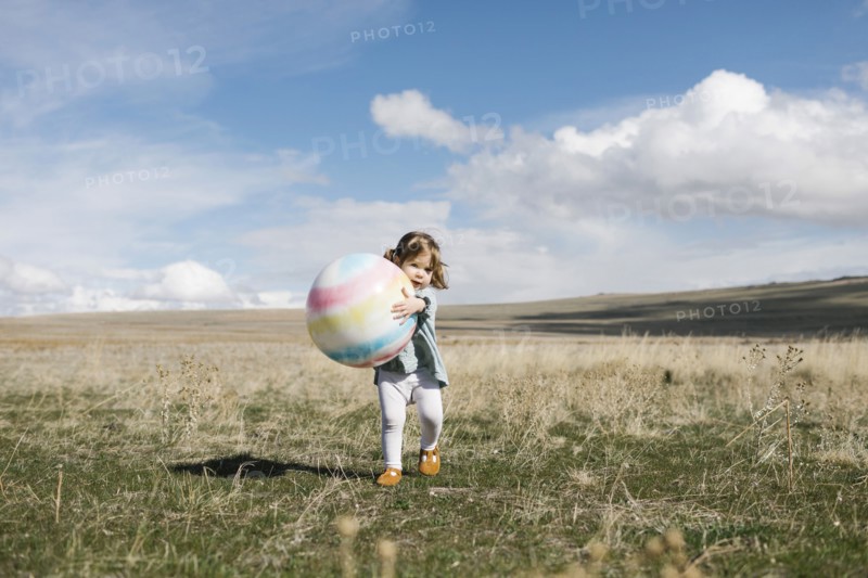Girl (2-3) holding ball in open field