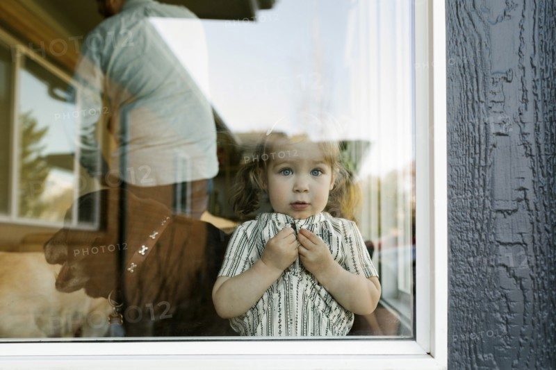 Girl (2-3) looking through window