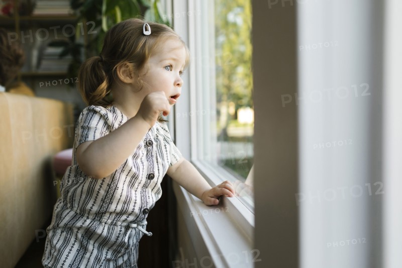 Girl (2-3) looking through window