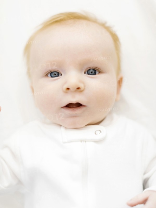 Portrait of baby boy (2-3 months) lying on bed