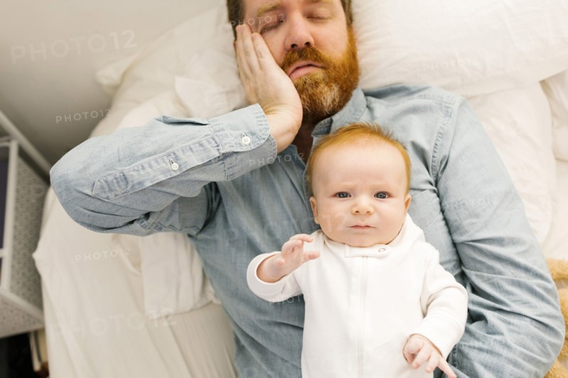 Father lying on bed with baby boy (2-3 months)