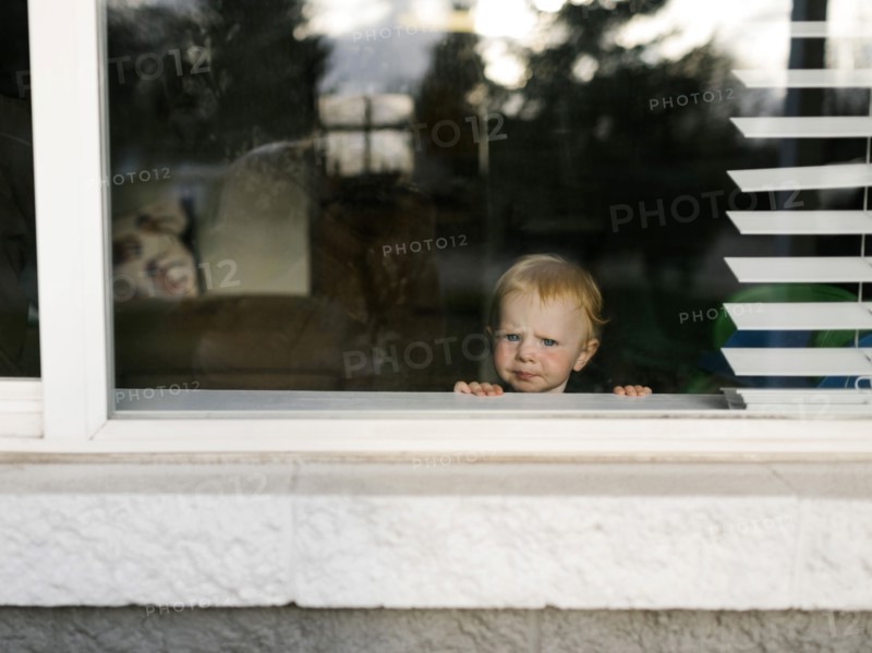 Girl (2-3) looking through window