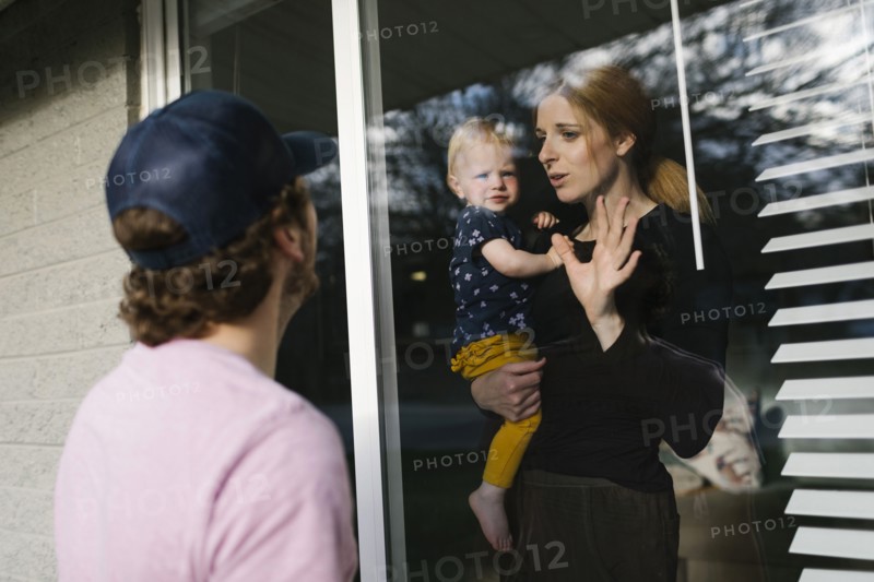 Mother with daughter (2-3) talking to man through window