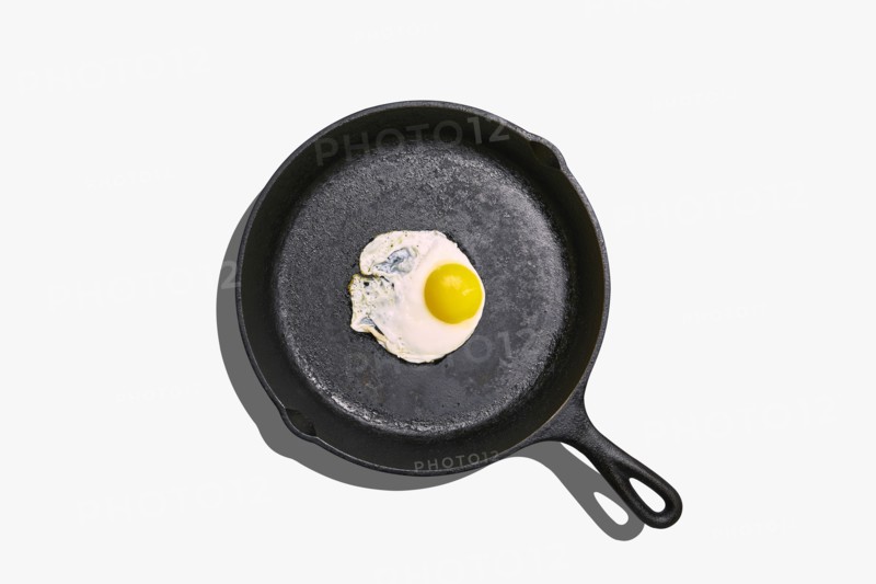 Overhead view of fried egg on frying pan on white background