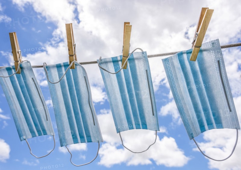 Row of surgical masks hanging on clothesline with sky in background