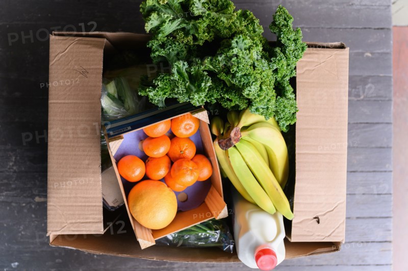 Overhead view of box of delivered produce on house porch