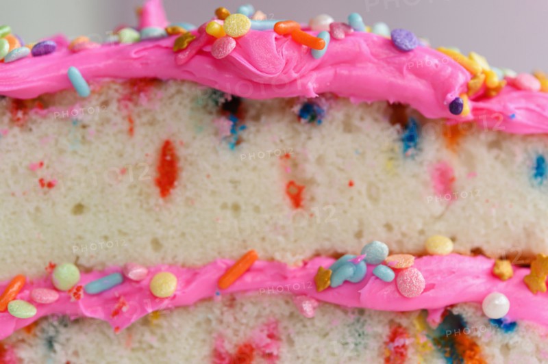 Colorful sprinkles on pink cake frosting