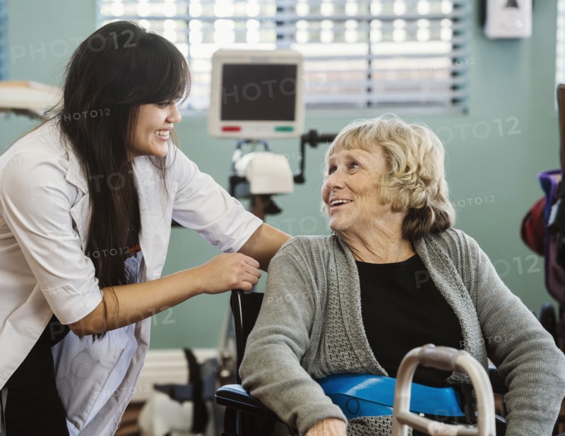 Nurse assisting senior woman in wheelchair in retirement home