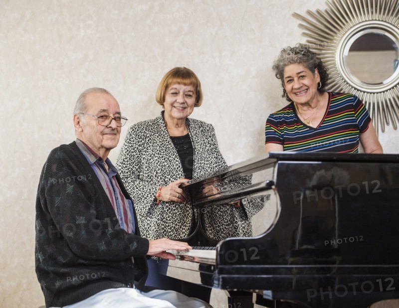 Senior women listening to man playing piano