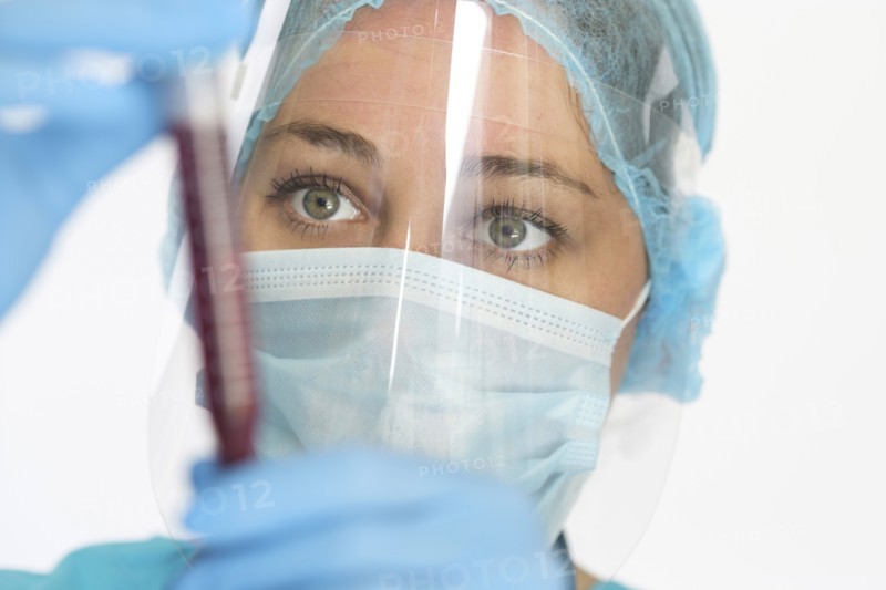 Nurse in mask and face shield holding blood sample
