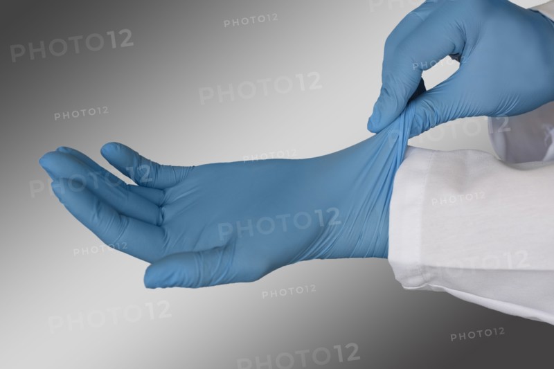 Person putting on blue surgical gloves