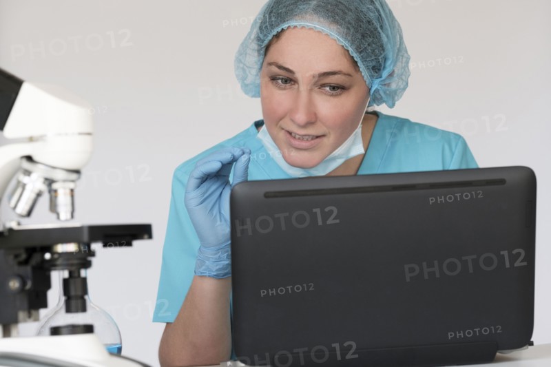 Woman in protective lab workwear sitting in front of laptop