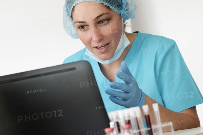 Woman in protective lab workwear sitting in front of laptop