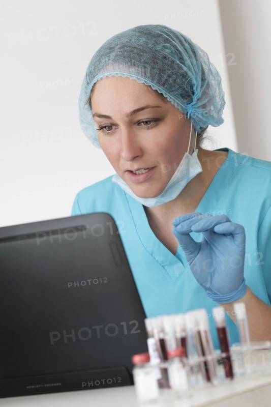 Woman in protective lab workwear sitting in front of laptop