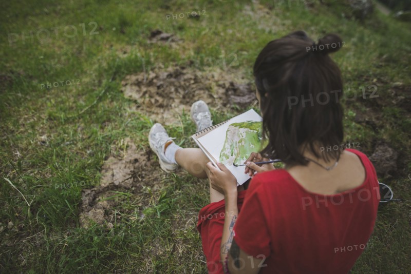 Switzerland, Obergoms, Young woman painting with watercolor in Swiss Alps