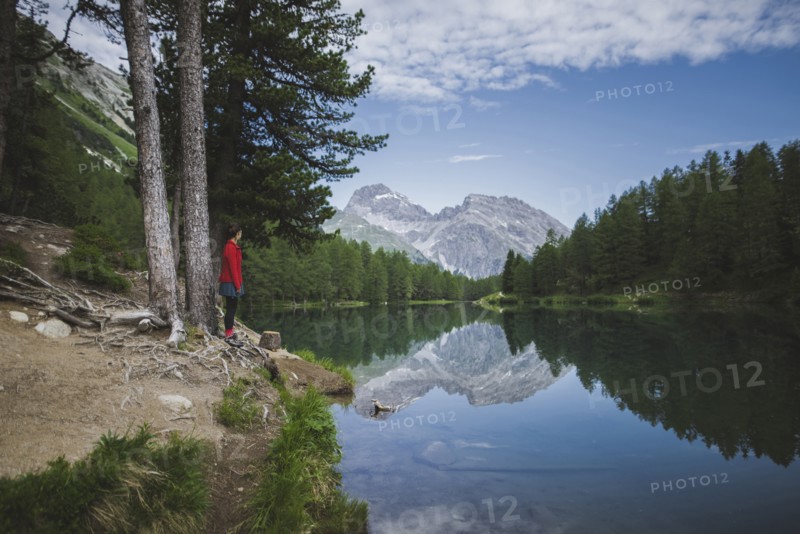 Switzerland, Bravuogn, Palpuognasee, Young woman resting on bench near Palpuognasee lake in Swiss Alps