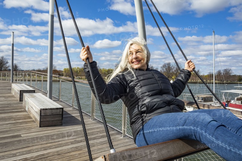 USA, Washington D.C., Senior woman on swing at Wharf District along Potomac River
