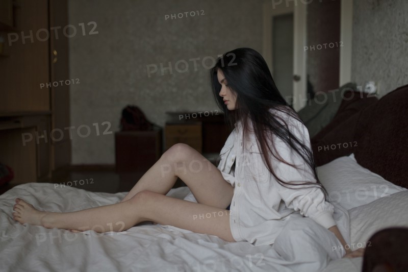 Semi-dress woman sitting on bed