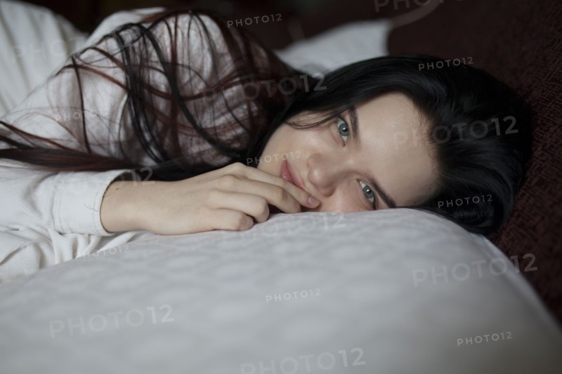 Portrait of young woman lying on bed