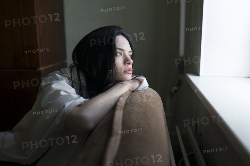 Young woman looking through window