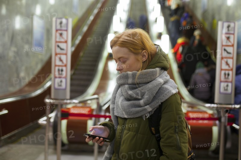 Russia, Novosibirsk, Young woman with smartphone standing by escalator