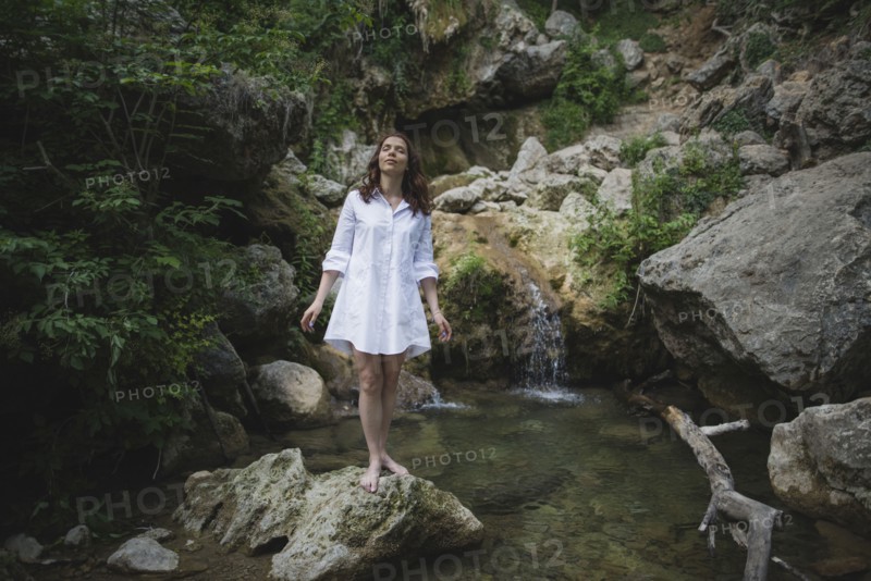 Ukraine, Crimea, Young woman standing on rock near waterfall