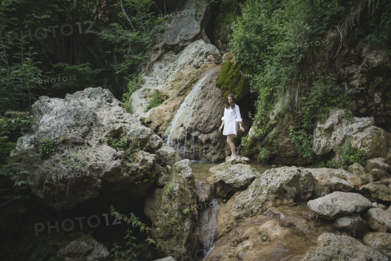 Ukraine, Crimea, Young woman walking barefoot on rocks in canyon