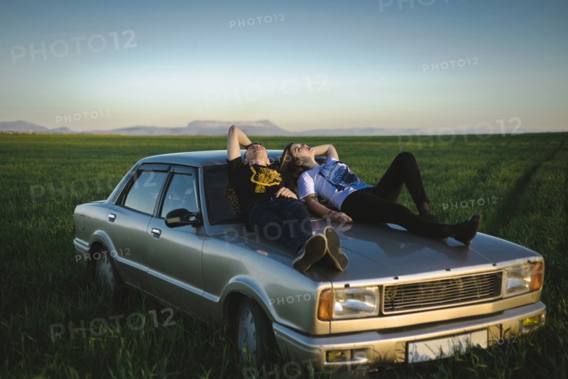 Ukraine, Crimea, Couple sitting on old fashioned car in rural scenery