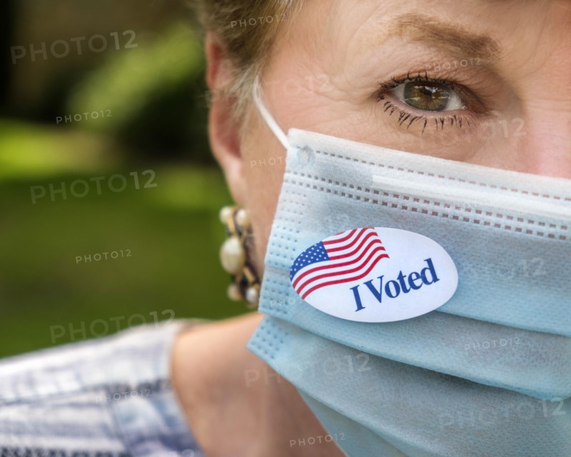 Close-up of woman in surgical mask and of I voted sticker