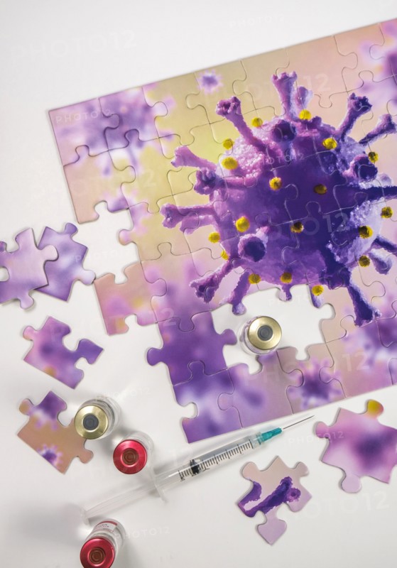 Studio shot of puzzle with Coronavirus model and vaccine vials and syringe