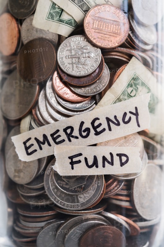 Close-up of coins and banknotes in jar labeled Emergency Found