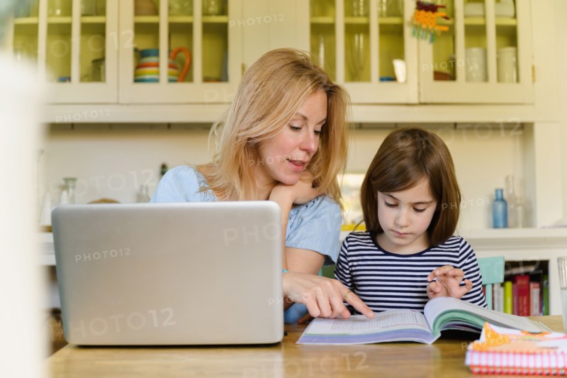 Mother helping daughter (6-7) doing homework