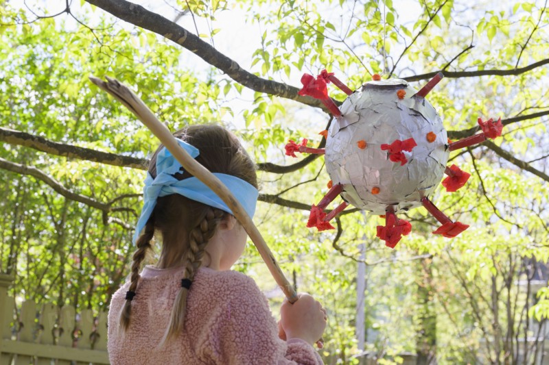 Girl (6-7) preparing to hit coronavirus shaped pinata