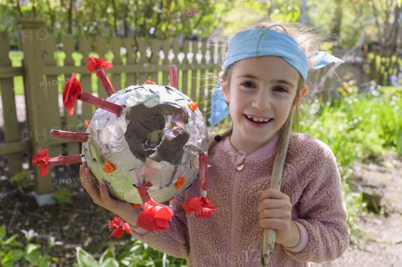 Smiling girl (6-7) holding coronavirus shaped pinata