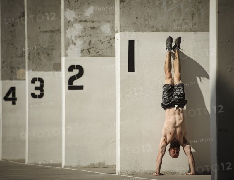Man doing handstand next to wall