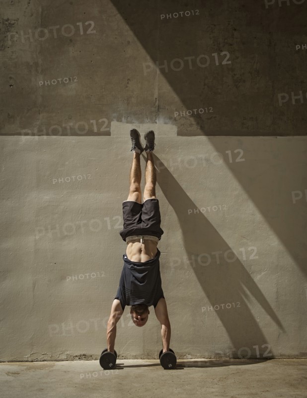 Man doing handstand next to wall