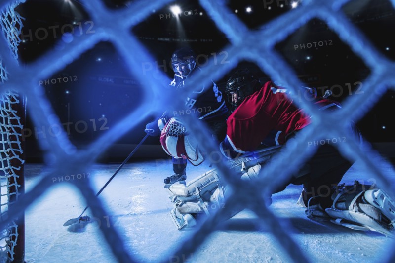 Hockey goalie defending net against forward