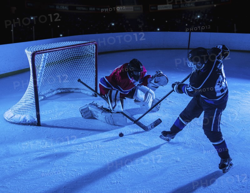 Hockey goalie defending net against forward