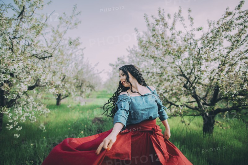 Young woman dancing in blooming orchard