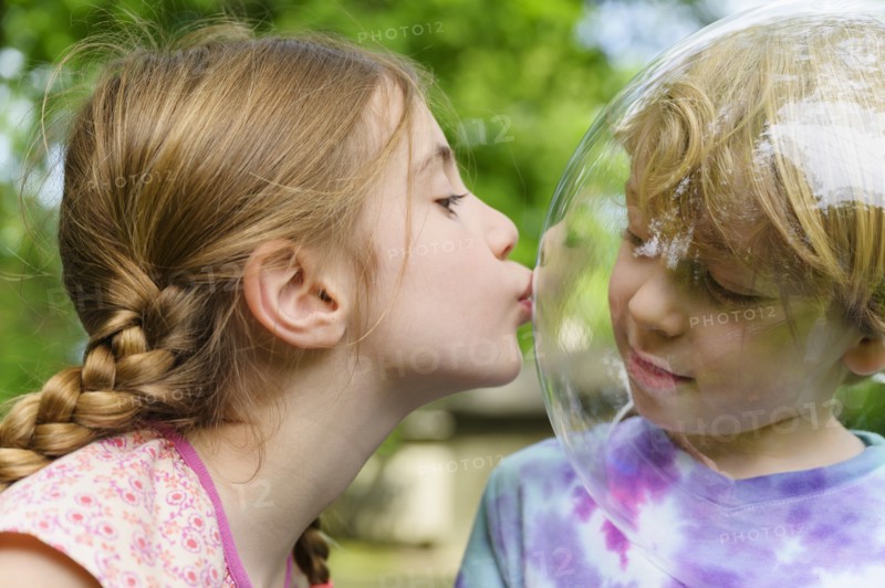 Girl kissing boy wearing bubble to socially distance