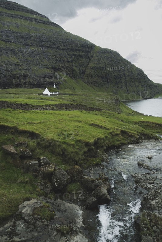 Denmark, Small church in green landscape with mountains and sea,