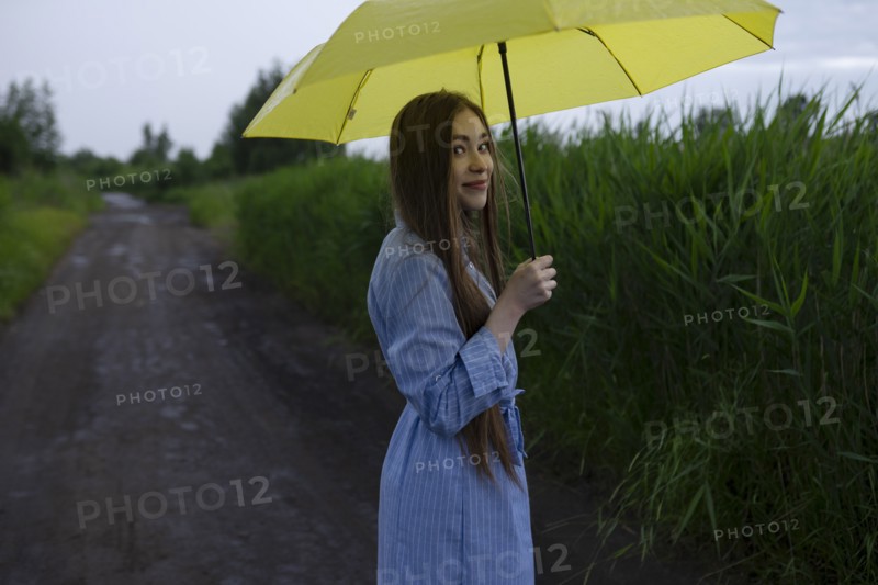 Russia, Omsk, Portrait of young woman with umbrella on dirt road