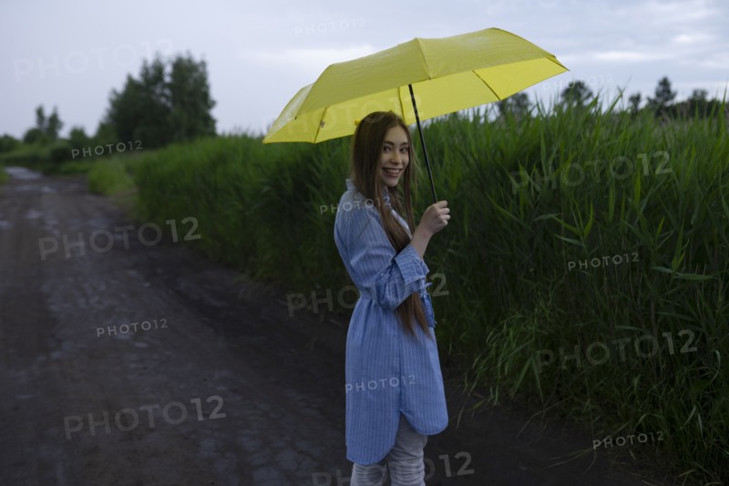 Russia, Omsk, Portrait of young woman with umbrella on dirt road