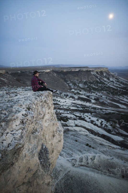 Ukraine, Crimea, Hiker sitting on edge of steep cliff near White Mountain