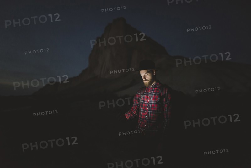 Ukraine, Crimea, Man in hat with glowing phone standing near White Mountain at night