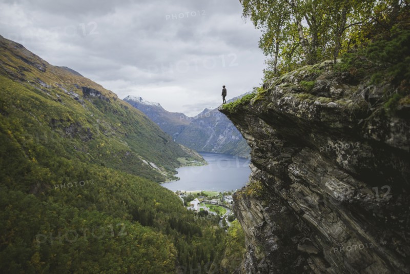 Norway, Geiranger, Man standing on edge of steep cliff above Geirangerfjord