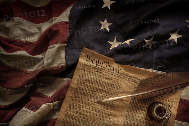 Constitution quill and ink lying on American flag