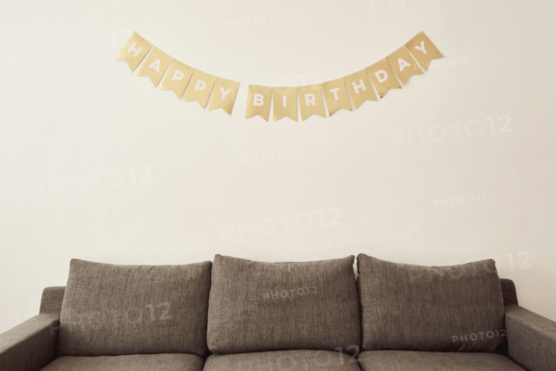 Happy birthday wishes on wall above sofa,,