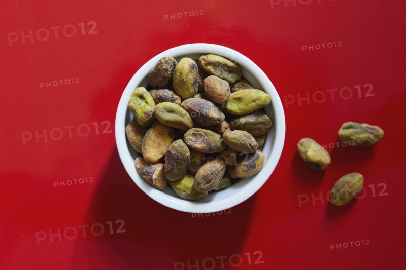 Pistachios in bowl on red background